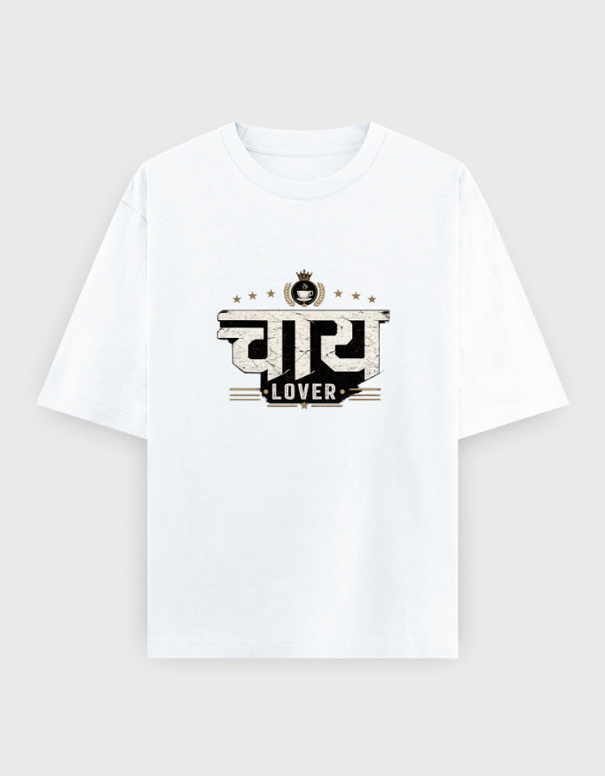 A white short-sleeve crewneck oversized t-shirt with a graphic print on the chest featuring the Hindi word 'सुबि' in a stylized black and beige font with the word 'LOVER' underneath, displayed on a light gray background.