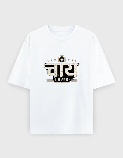 A white short-sleeve crewneck oversized t-shirt with a graphic print on the chest featuring the Hindi word 'सुबि' in a stylized black and beige font with the word 'LOVER' underneath, displayed on a light gray background.