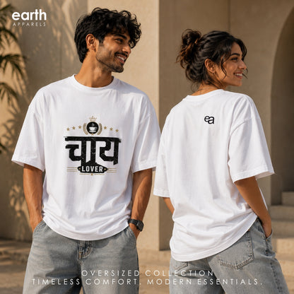 A man and a woman modeling an oversized white t-shirt from Earth Apparel. The man is shown from the front, wearing a white t-shirt with a black Hindi graphic that reads 'CHAI LOVER' under a crown.