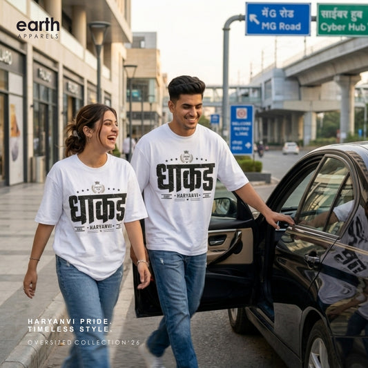 A man and a woman walking and smiling next to a black car on a city street, wearing matching white oversized t-shirts with a bold black Hindi graphic print that reads 'EJAAD' and 'HARYAVANTRI'. The 'earth APPAREL' brand logo is visible in the top left corner.