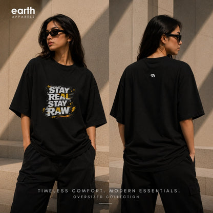 A model shown from the front and back wearing an oversized black t-shirt. The front features a graphic print with the text 'STAY REAL STAY RAW' in white, yellow, and black.